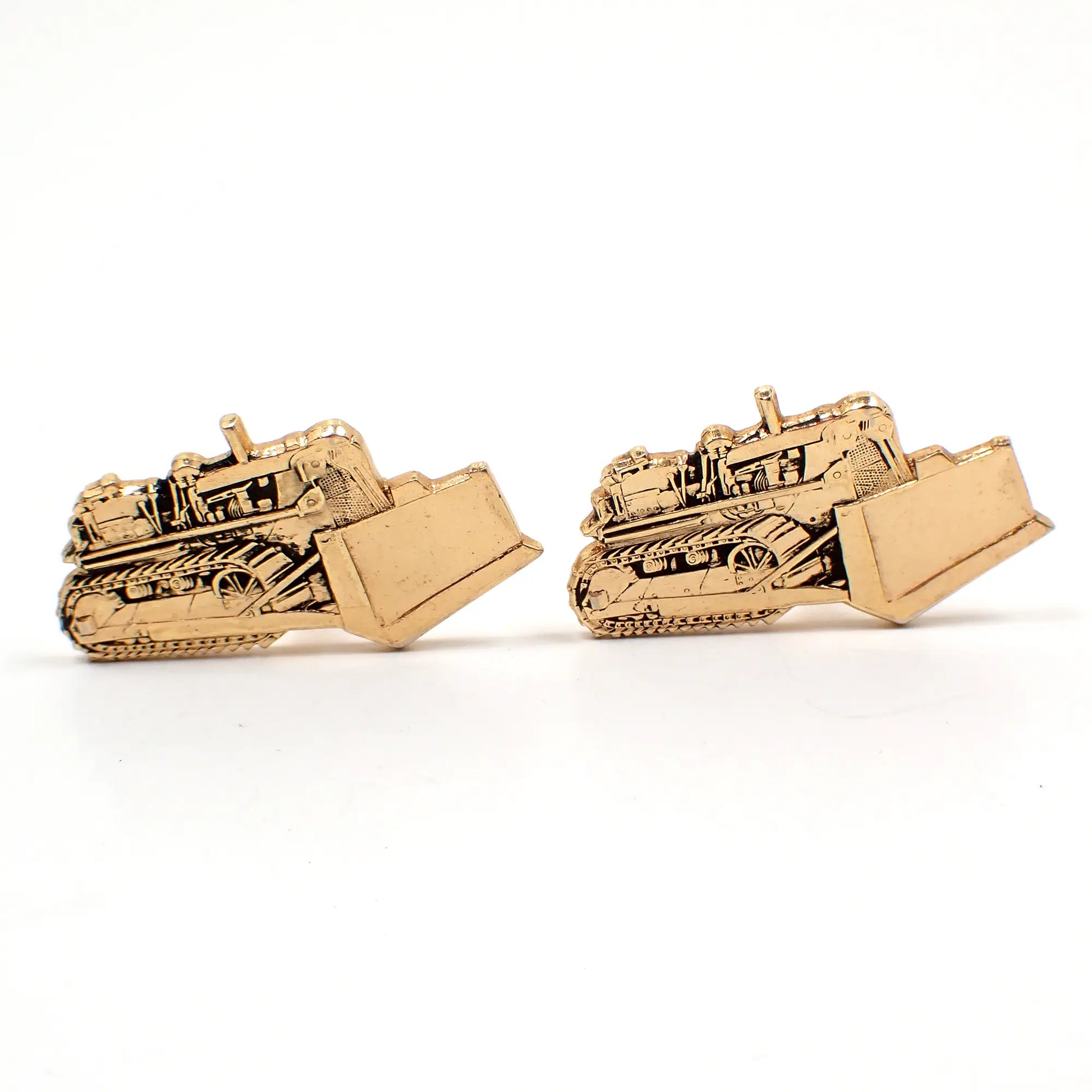 Front view of the retro vintage bulldozer cufflinks. They are gold tone in color and have a textured bulldozer heavy equipment design.