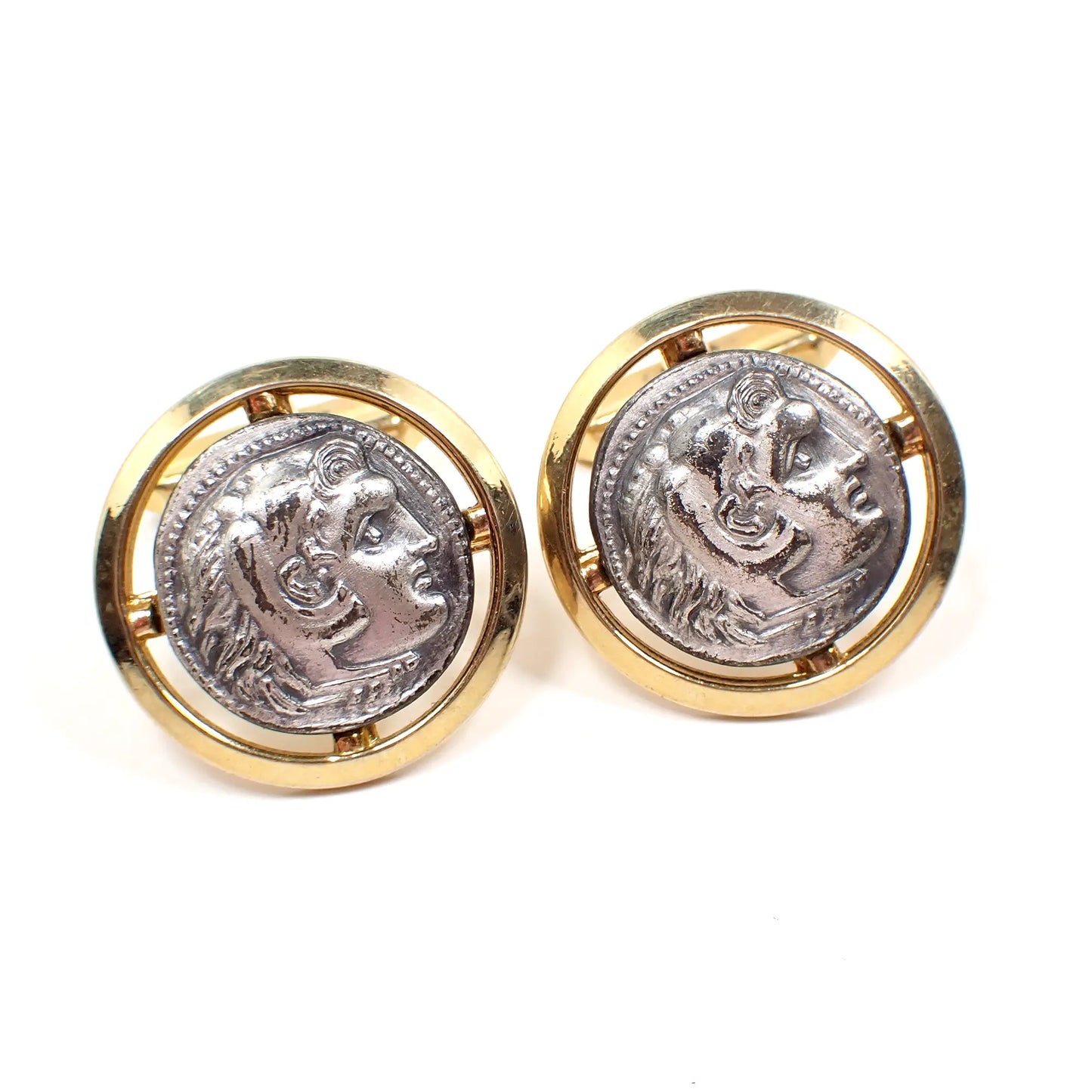 Front view of the Mid Century vintage two tone metal cameo cufflinks. They are round and have light pewter gray fronts with a raised design of Alexander the Great. The outer edge has a cut out design and gold tone color metal.