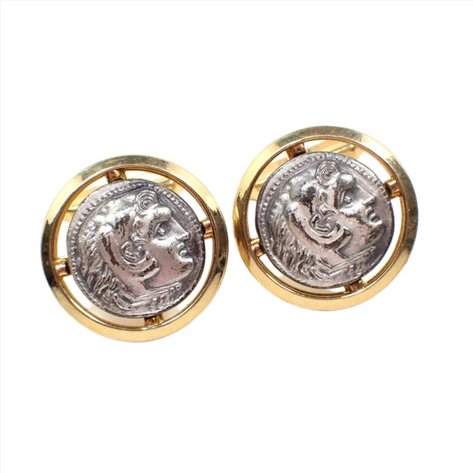 Front view of the Mid Century vintage two tone metal cameo cufflinks. They are round and have light pewter gray fronts with a raised design of Alexander the Great. The outer edge has a cut out design and gold tone color metal.