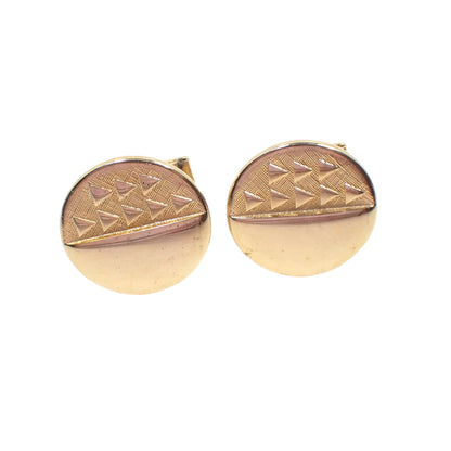 Front view of the 1960's Mid Century vintage cufflinks. They are gold tone in color and round in shape. Half of the front has a matte textured surface with raised shiny triangle design and the other half is shiny gold tone metal.