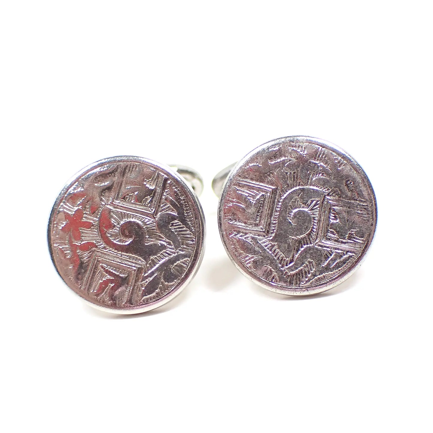 Front view of the 1930's vintage bean back cufflinks. The metal is silver tone in color. They are round and have a design with abstract leaf like shapes. 