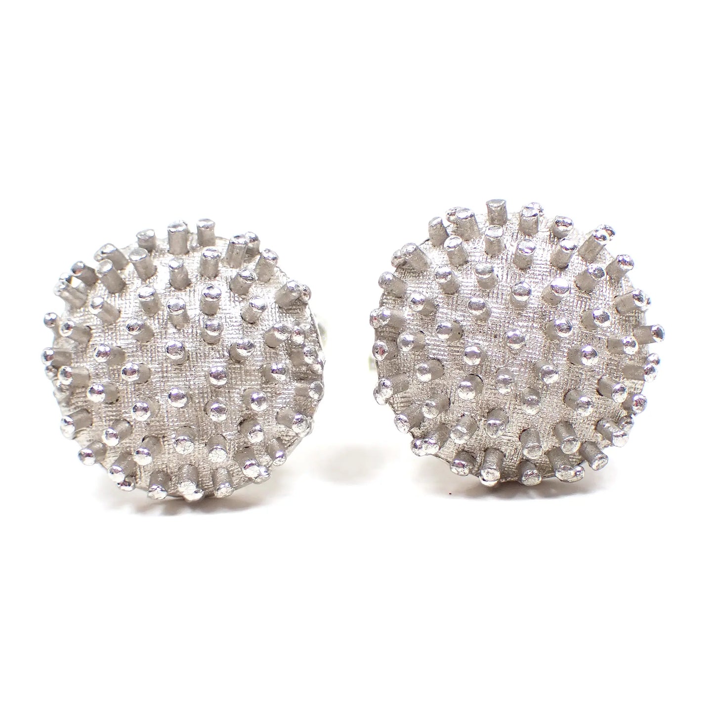 Front view of the Mid Century vintage Dante cufflinks. They are round and silver tone in color with a Brutalist style bumpy textured pattern along the front.