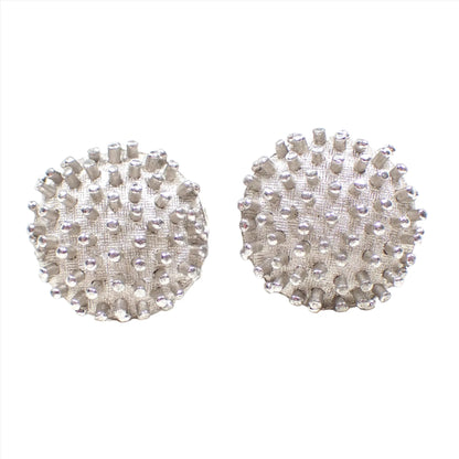 Front view of the Mid Century vintage Dante cufflinks. They are round and silver tone in color with a Brutalist style bumpy textured pattern along the front.