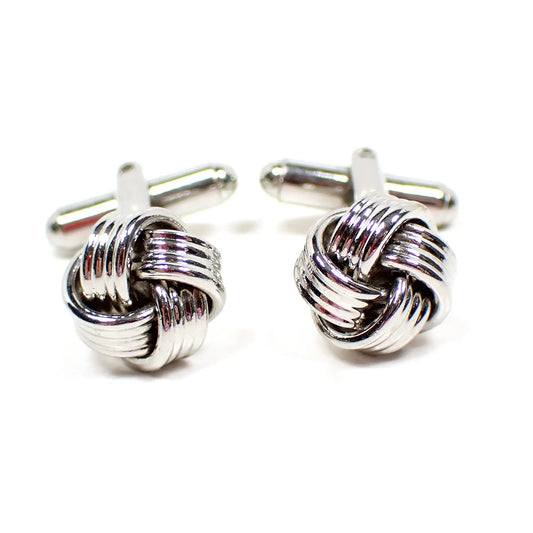 Front view of the retro vintage knot cufflinks. The metal is silver tone in color. The knots are woven with silver color metal that has textured stripes. 