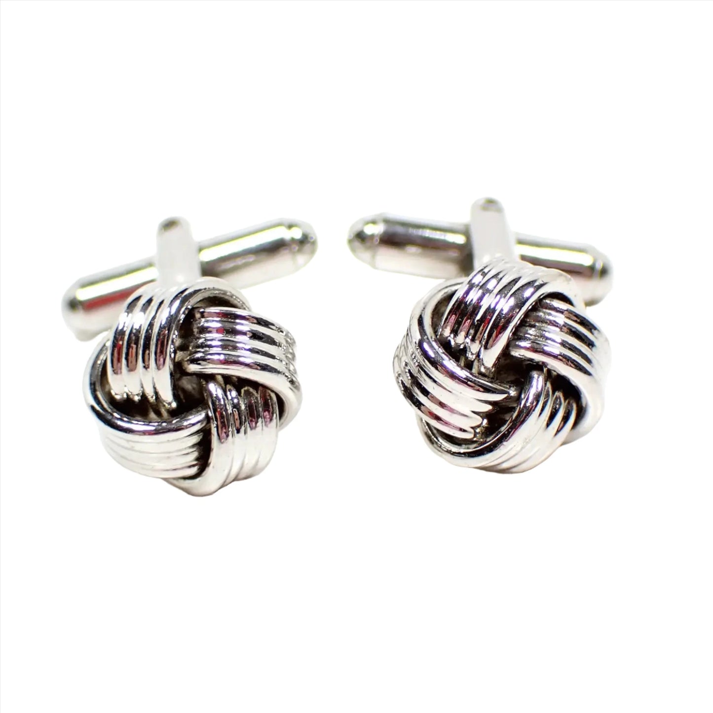 Front view of the retro vintage knot cufflinks. The metal is silver tone in color. The knots are woven with silver color metal that has textured stripes. 
