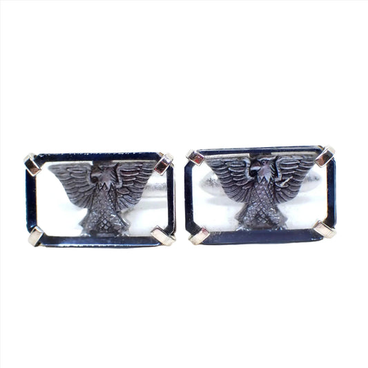 Front view of the retro vintage Swank cufflinks. The metal is silver tone in color. They are shaped like rectangles and have a transparent blue glass front with a silver tone eagle design behind it. The eagle has his wings spread.