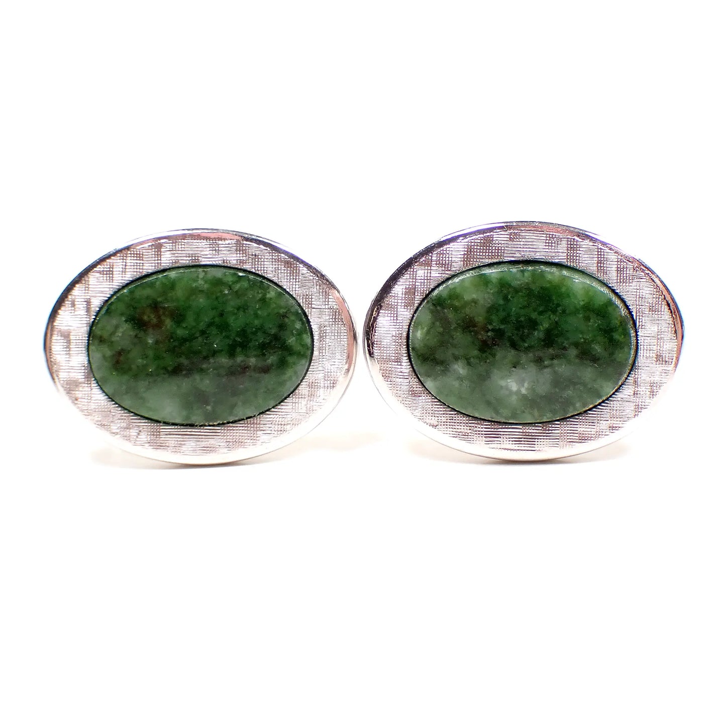 Front view of the retro vintage Krementz cufflinks. The metal is silver tone color and has a brushed matte appearance on the fronts. They are oval in shape with green moss agate gemstone cabs in the middle. The gemstone cabs have different shades of green. 