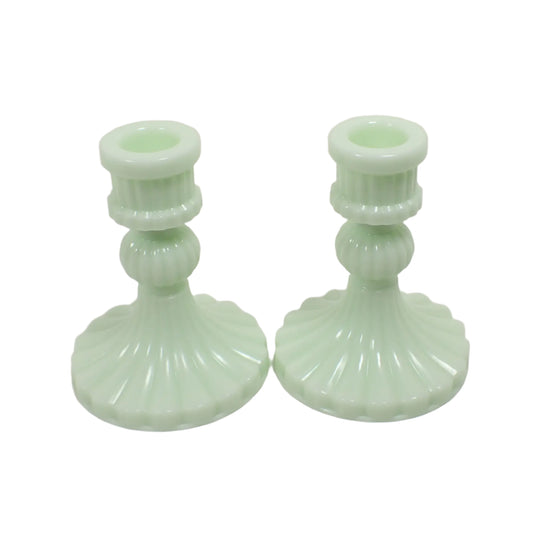 Angled side view of the handmade candlestick holders. The resin is a light pastel green lime cream color. They have a flared bottom and corrugated design all the way around them for a vintage style appearance.