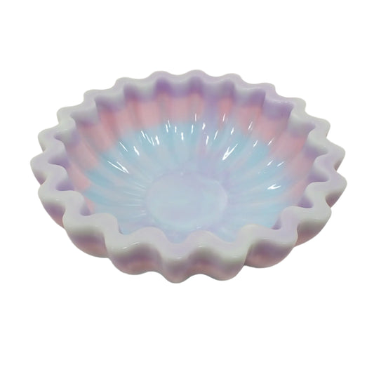 Angled view of the handmade multi color resin scalloped bowl. It has very light green at the top, then purple, pink, and light blue. 