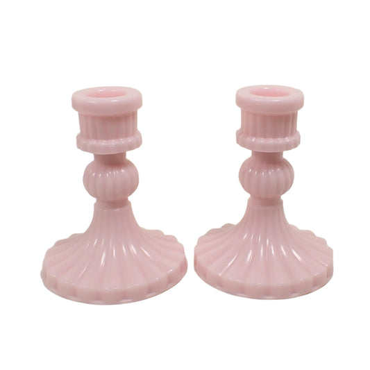 Angled side view of the handmade pastel pink candle holders. The resin is a light cotton candy pink in color. They have a corrugated line design all the way around the outside of the holders.