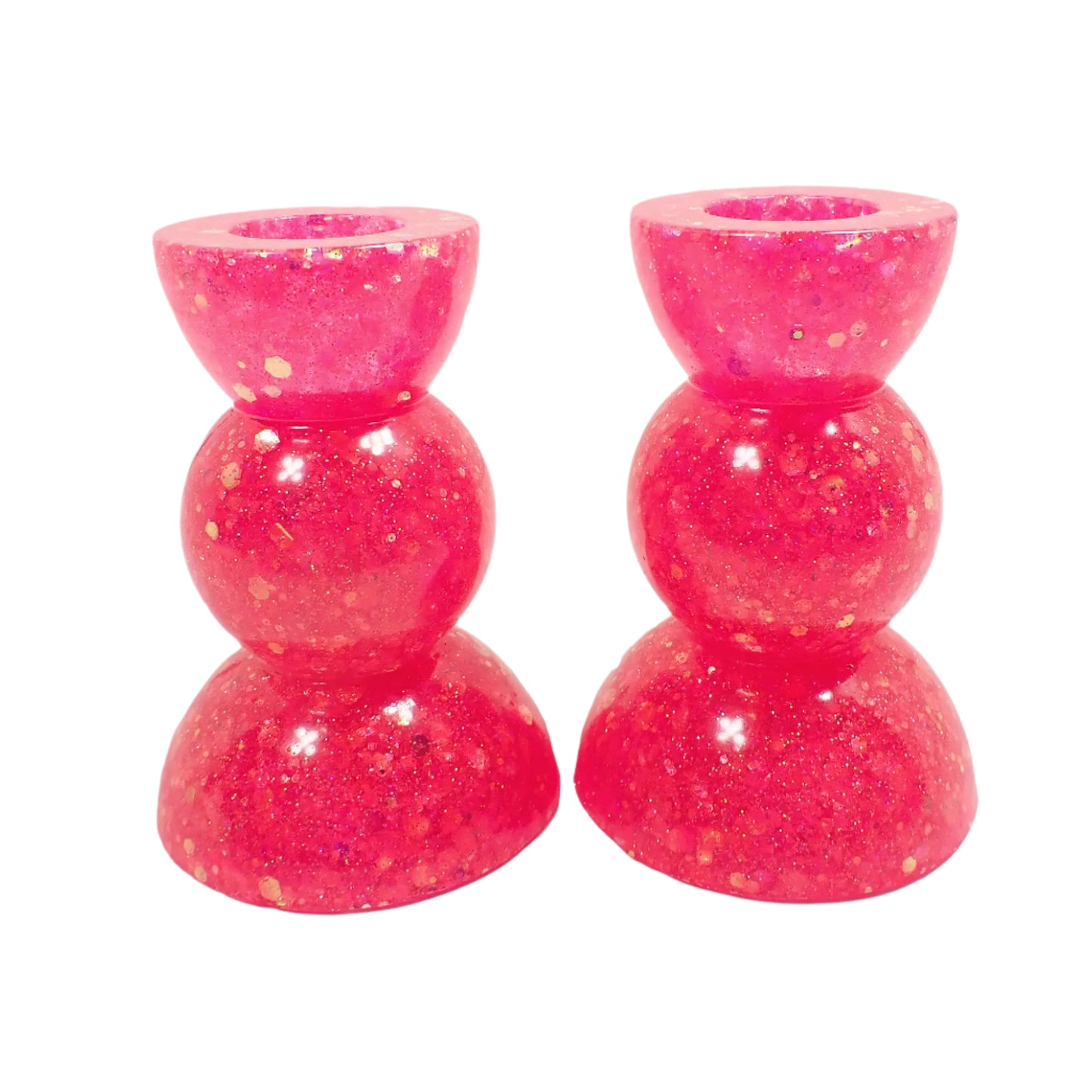 Angled photo of the handmade geometric style resin candle holders. There is bright pink chunky iridescent glitter throughout. Flashes of sparkle can be seen in the photo from the glitter as the light is hitting it.