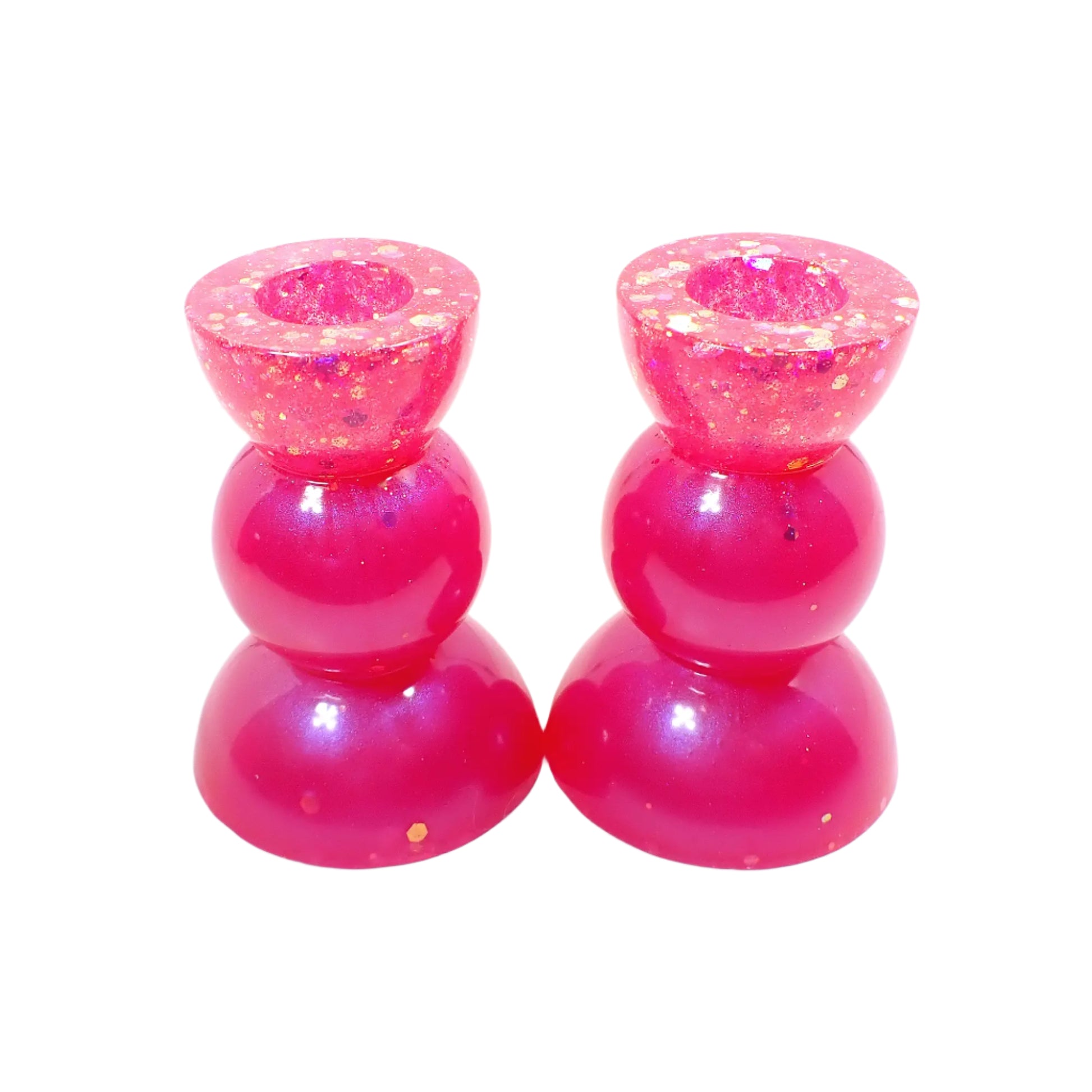 Angled view of the handmade resin geometric style candle holders. They have bright pearly pink resin with chunky pink iridescent glitter on top and a few sparkles throughout.