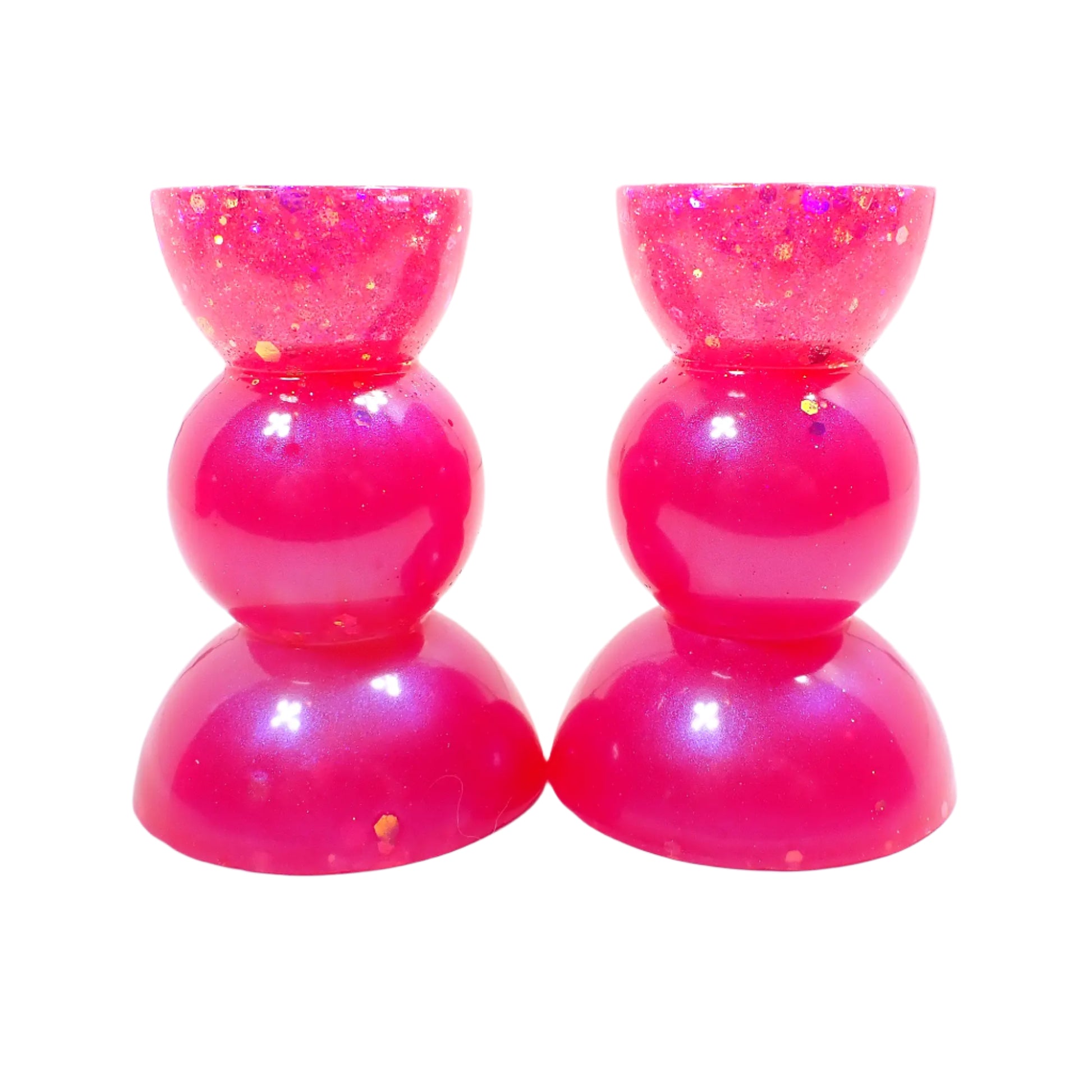 Side view of the handmade bright pink candle holders with glitter. There is a half sphere shape at the top and bottom with a rounded sphere shape in the middle for a geometric style appearance.