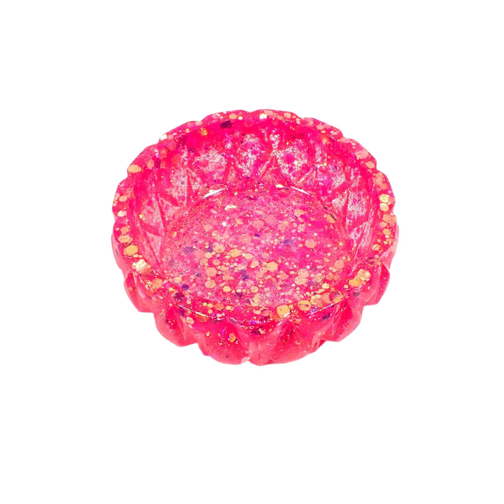 Angled view of the handmade bright pink glitter ring dish. It is round with a faceted diamond shape geometric design around the outside edge. The resin has iridescent chunky pink glitter throughout.