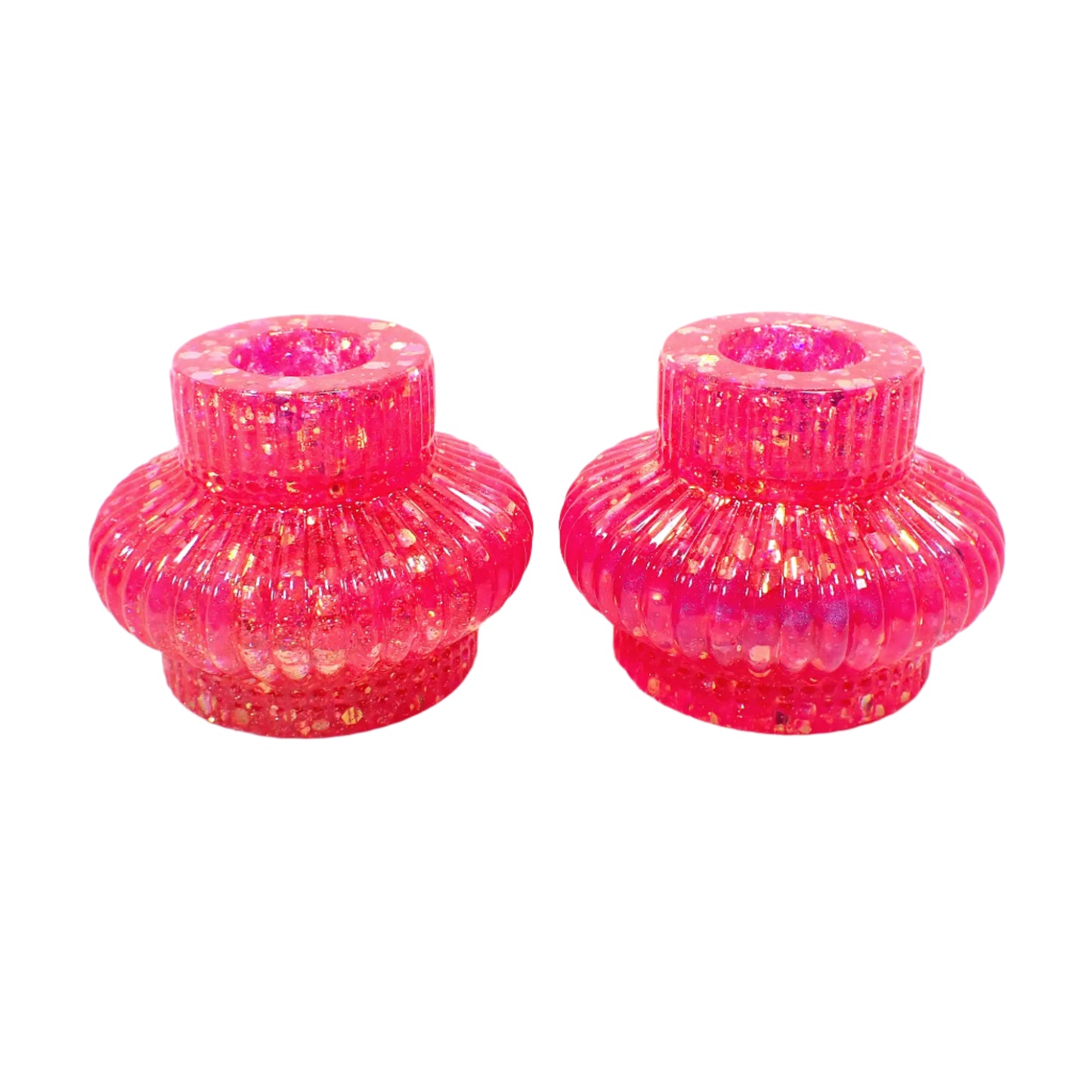 Angled side view of the handmade resin candle holders. They have bright pink iridescent chunky glitter throughout.