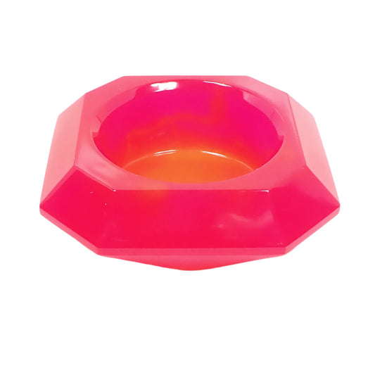 Angled side view of the handmade neon pink and orange faceted octagon decorative bowl. It is tapered on the bottom and has a round opening on the top. The resin is semi translucent.