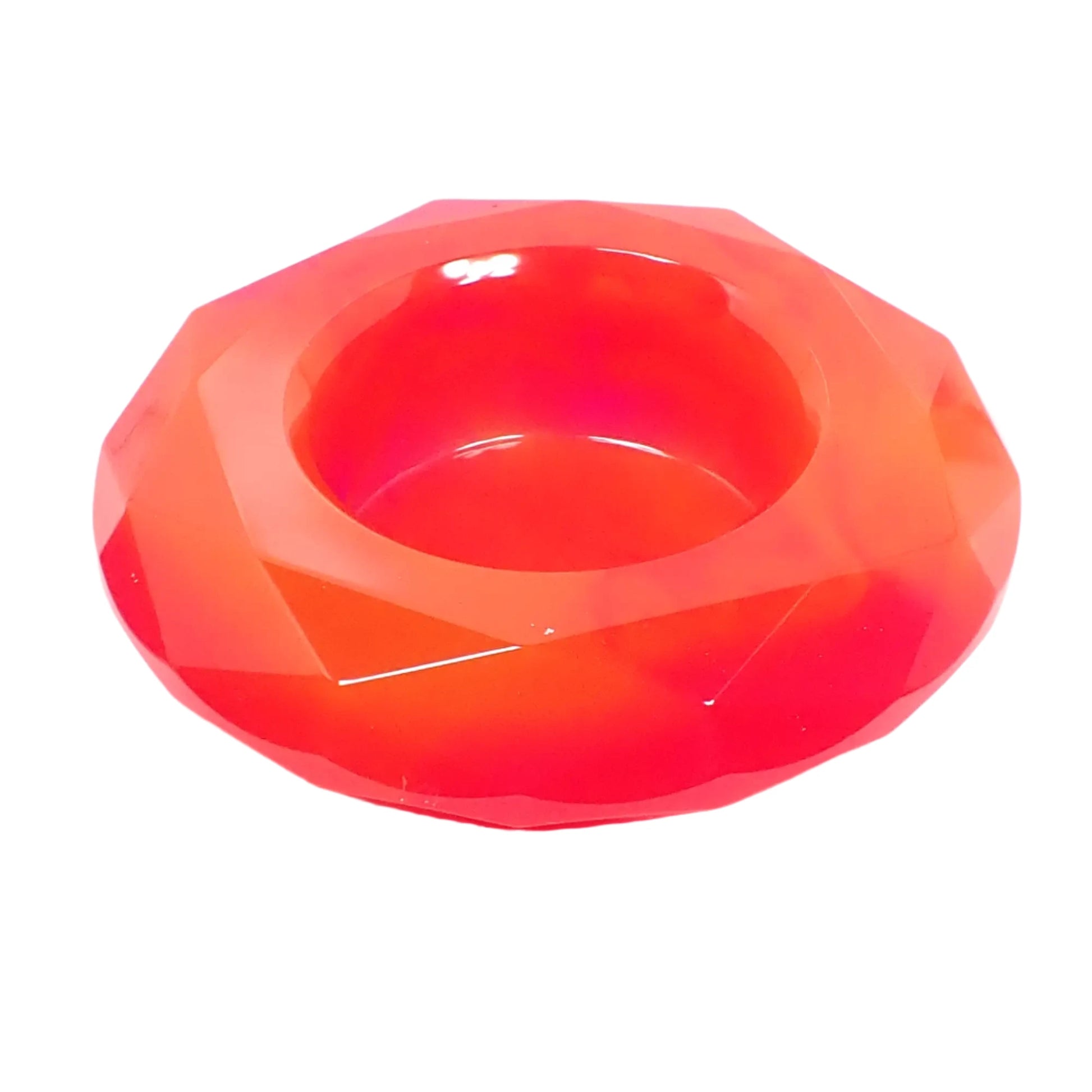 Angled view of the handmade resin faceted round decorative bowl. It is faceted and shaped similar to a round cut gemstone. There is a round opening at the top to put small things. The color is marbled with bright neon pink and orange.