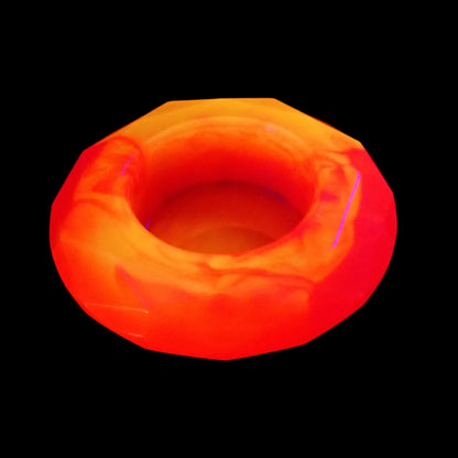 Photo of the faceted round neon pink and orange bowl showing how the colors fluoresce under a UV light.