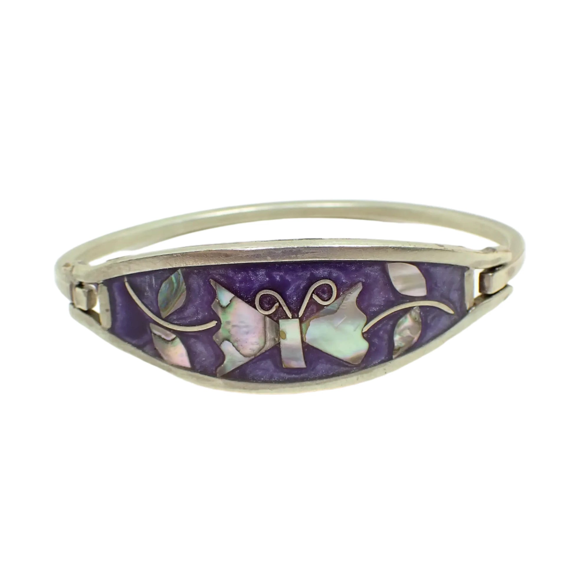 Front view of the vintage Alpaca butterfly hinged bangle bracelet. The metal is silver tone in color. The front has pearly purple resin enamel. There is a butterfly in the middle with leaves on either side made up of inlaid abalone shell. 