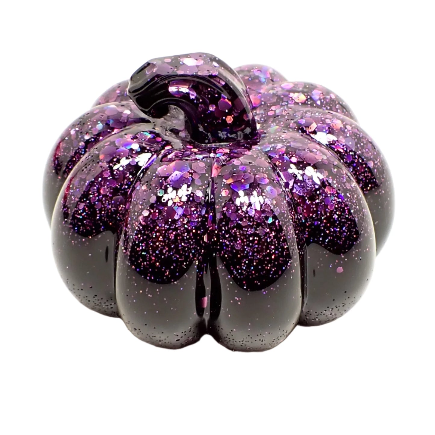 Angled view of the small resin pumpkin. It has shiny black resin with sparkly purple iridescent chunky glitter at the top and stem part of the pumpkin.