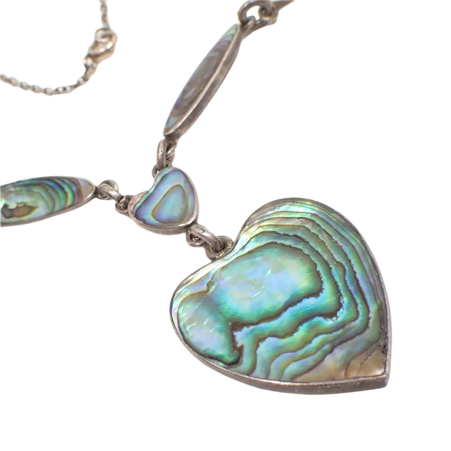 Enlarged photo showing a close up of the hear pendant and how the abalone shell has variations in color as the light hits it.