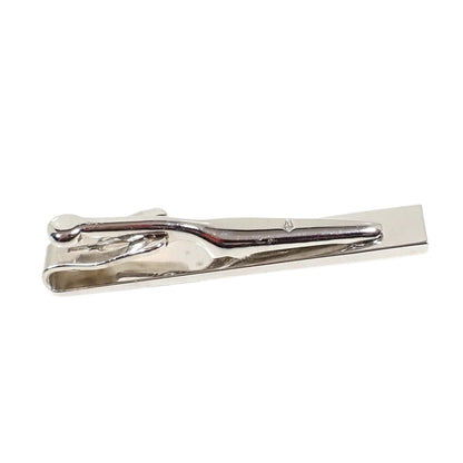 Back side view of the vintage Swank tie clip. The metal is shiny silver tone in color. There is a small Swank marking of a tie symbol with an S inside it stamped on the clip itself.