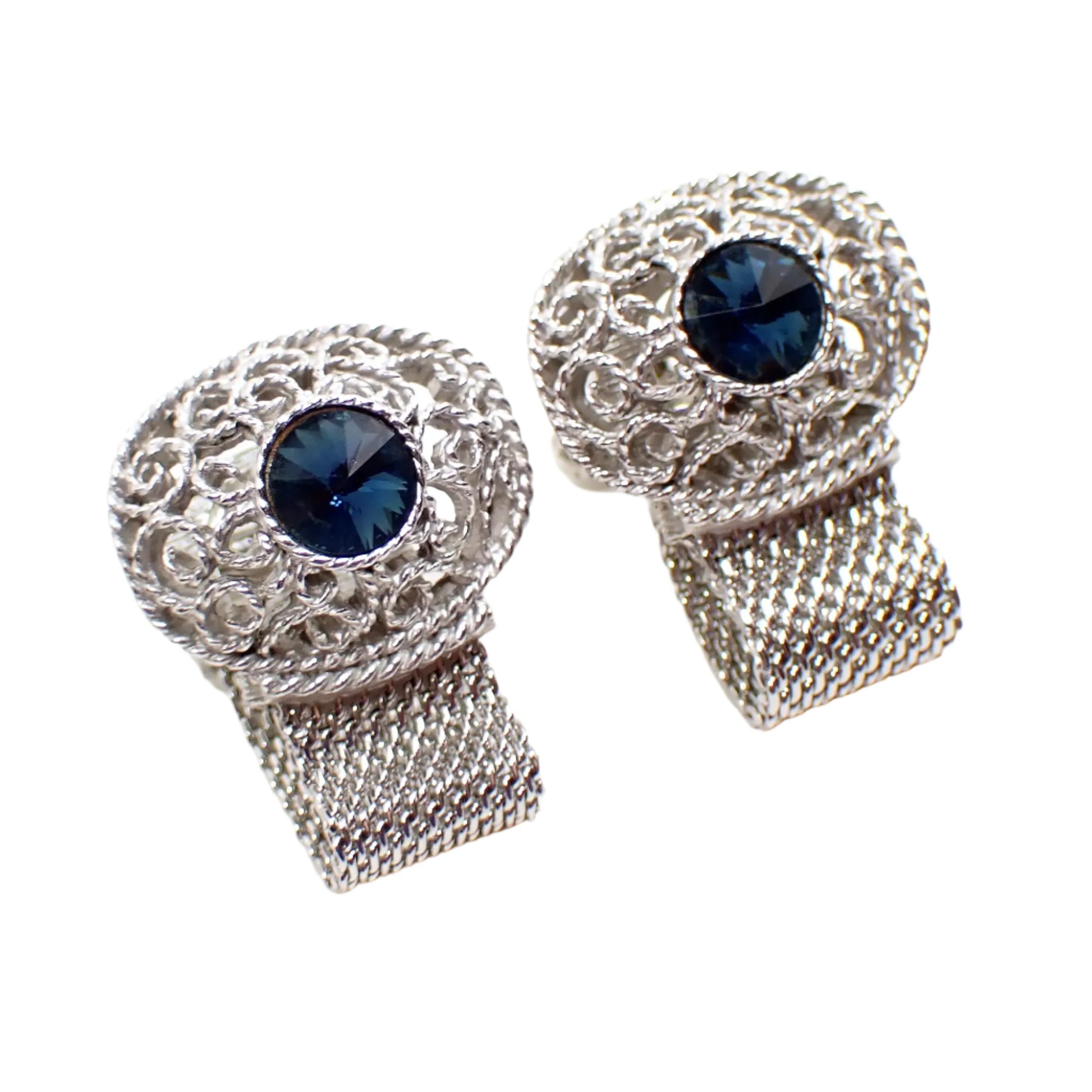 Angled view of the Swank wrap around mesh cufflinks. The filigree design has curls of twisted metal with spaces in between in the large oval area at the top.