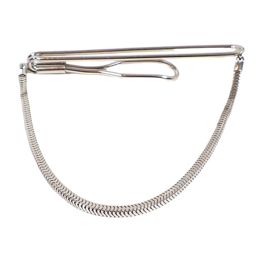 Front view of the Mid Century vintage Swank tie chain bar. It has a long oval open wire style design at the top. A snake chain is connected to each end of the tie bar and is hanging downward.