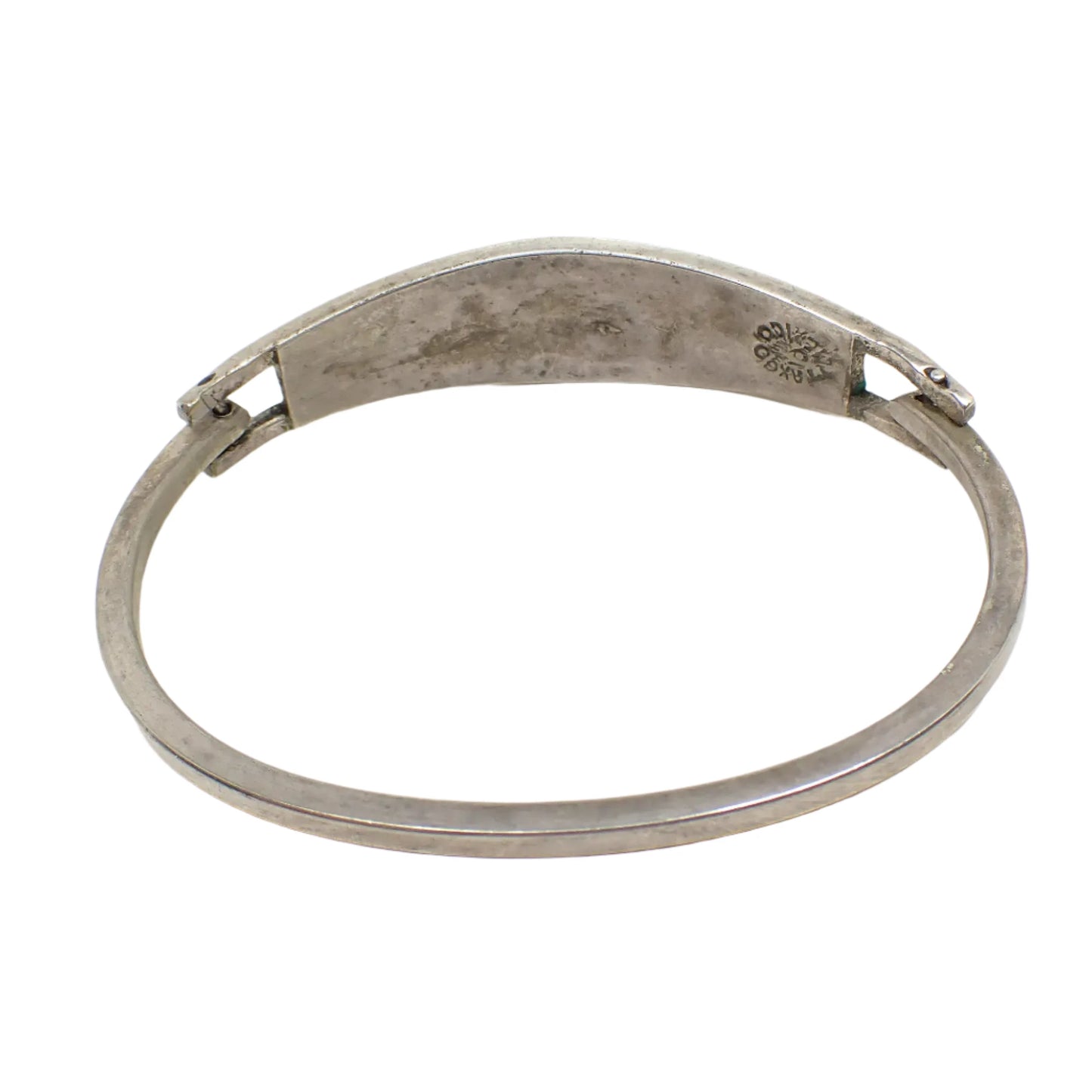 Back side photo of the hinged bangle. The inside has a darkened patina with some gray areas. The Taxco marking can be seen by the hinge as well as a small green spot of enamel overflow.