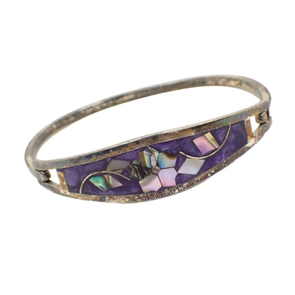 Angled photo of the vintage Taxco hinged bangle bracelet. The inlaid pieces of abalone shell have flashes of different colors in them.