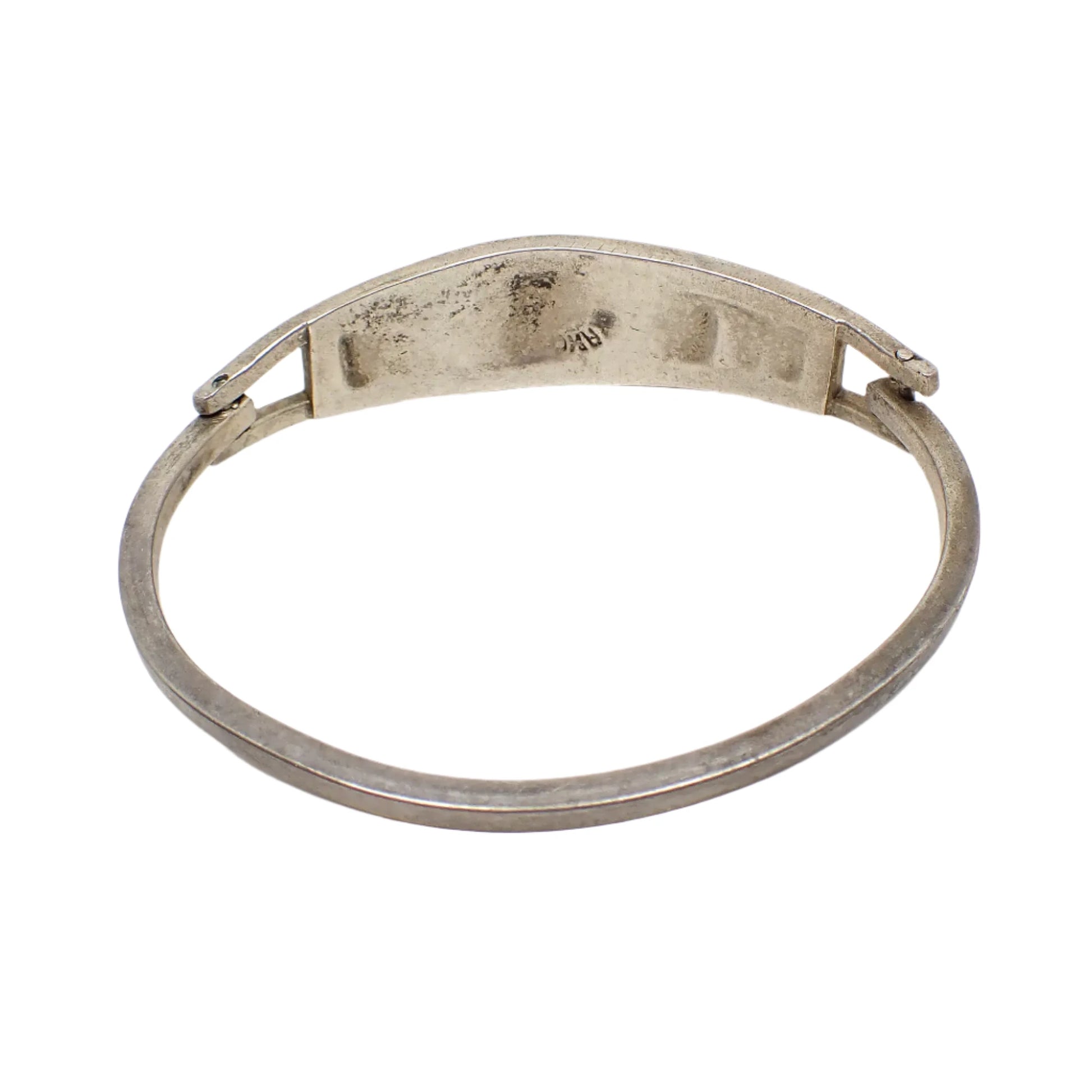 Back view of the vintage Taxco hinged bangle bracelet. The metal is antiqued silver in color. Part of the Taxco marking can be seen on the back of the bracelet in the photo.