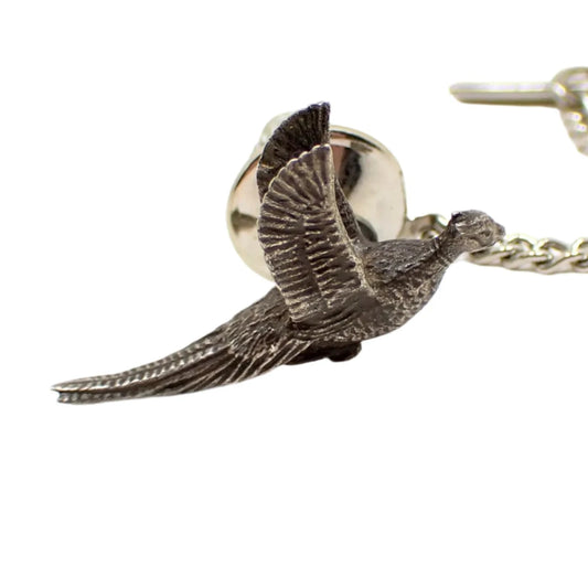 Enlarged view of the vintage tie tack. It has a 3D pheasant design. The bird is done in pewter and the clutch and chain are silver tone in color.