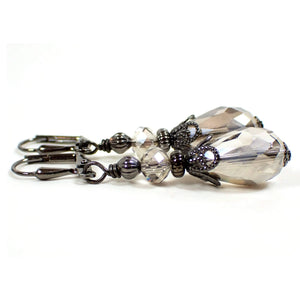 Side view of the handmade teardrop earrings. The metal is gunmetal gray in color. there are light smoky gray faceted glass crystal rondelle beads at the top and teardrop shaped beads at the bottom.