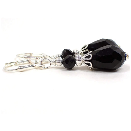 Side view of the Goth vintage style handmade earrings. The metal is silver plated in color. There are black faceted glass crystal beads at the top and teardrop shaped ones at the bottom.