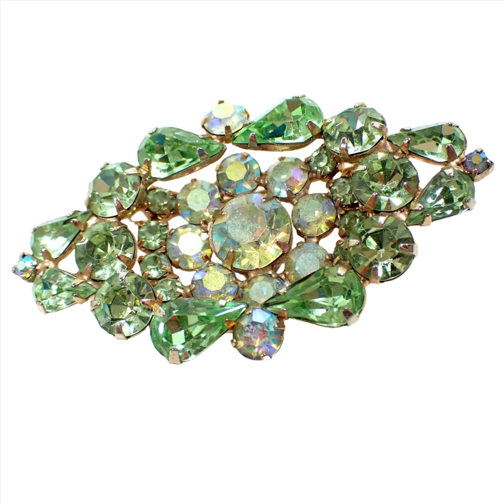 Front view of the Mid Century vintage Weiss crystal rhinestone brooch pin. The metal is gold tone in color and it is shaped like a tiered wide diamond shape. There are green teardrop and round rhinestones and AB round green rhinestones making up the entire front of the brooch.