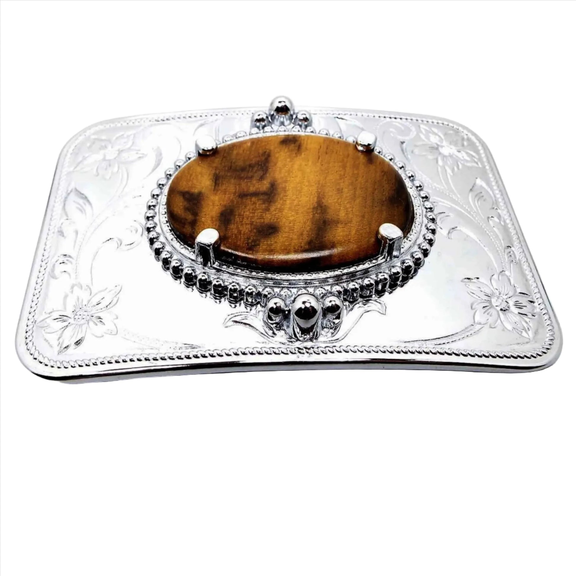 Front view of the retro vintage Reddscraft myrtlewood vintage belt buckle. The buckle is silver tone in color with a stamped floral design around the corners. The middle has a prong set oval cab of myrtlewood wood in shades of brown.