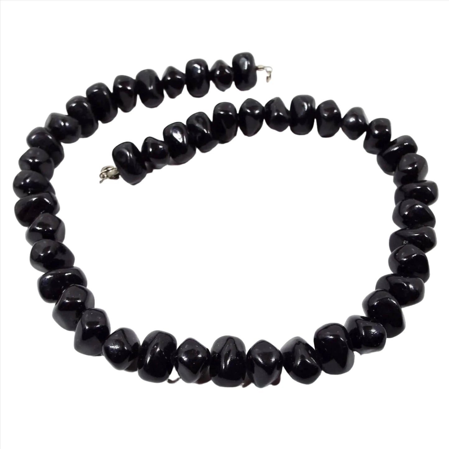 Front view of the retro vintage black beaded necklace. The beads are chunky nugget style black plastic beads. There is a silver tone spring ring clasp at the end.