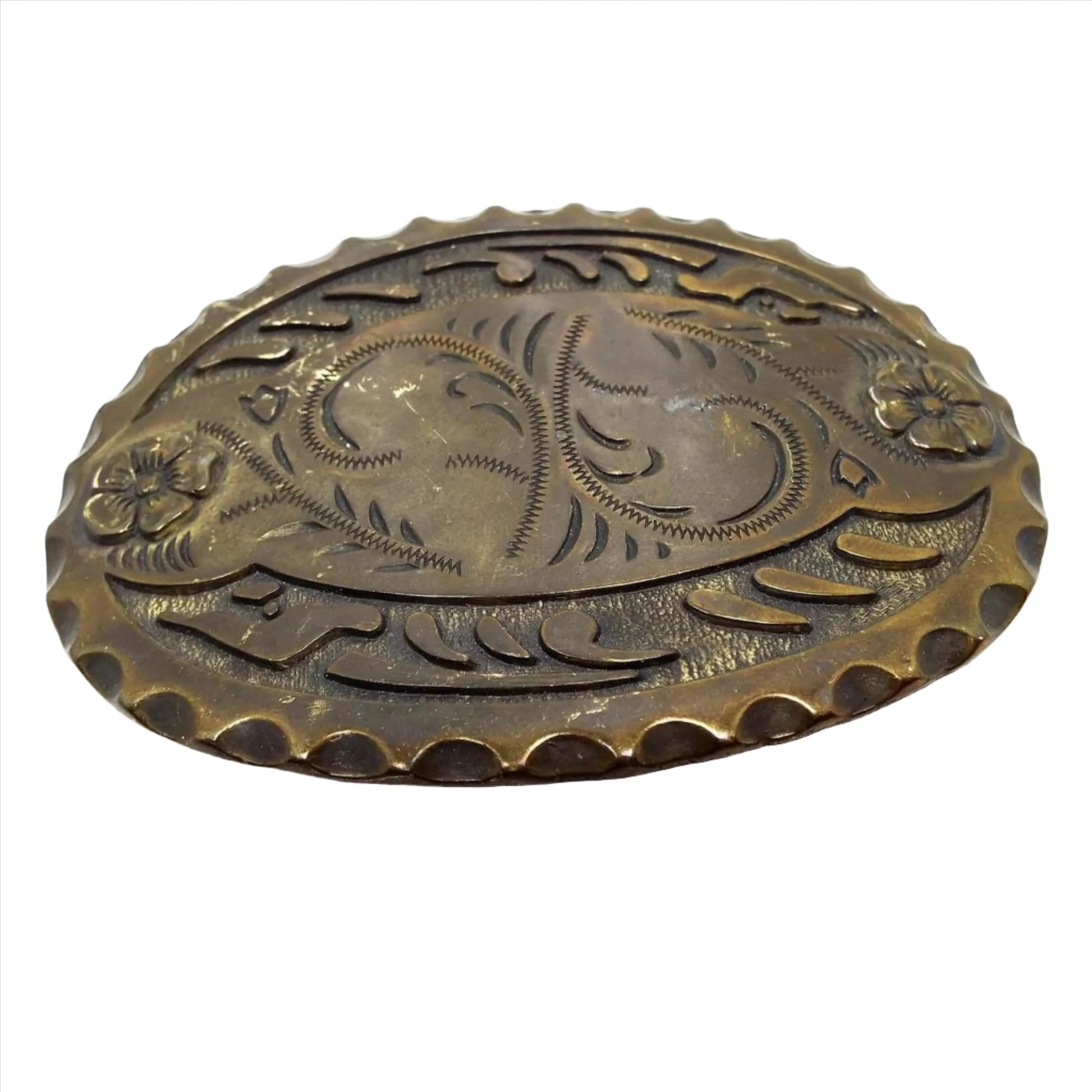 Front view of the retro vintage antiqued brass oval belt buckle. It has a scalloped edge and a cut floral design on the front.
