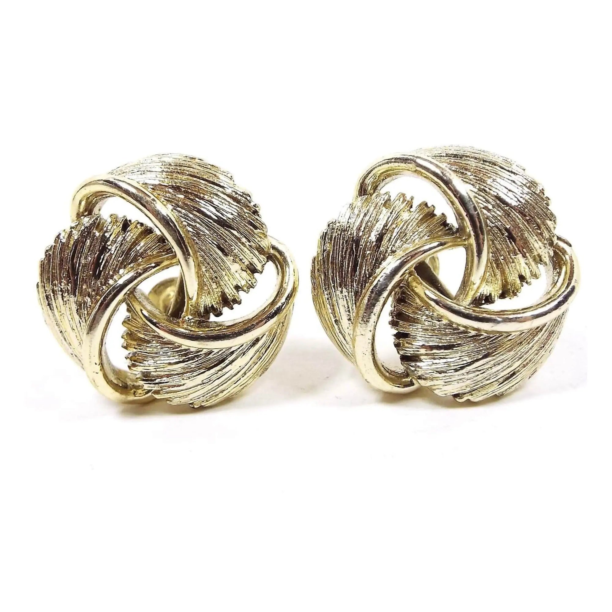 Front view of the Mid Century vintage Lisner screw back earrings. They are gold tone in color and look like three feather like areas that are twisted and curved around in a round type shape.