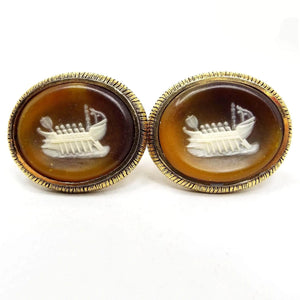 Front view of the Mid Century Vintage Dante Incolay cufflinks. The metal is gold tone in color. They are large ovals with a ship cameo on the front in shades of brown, cream, and white incolay stone.
