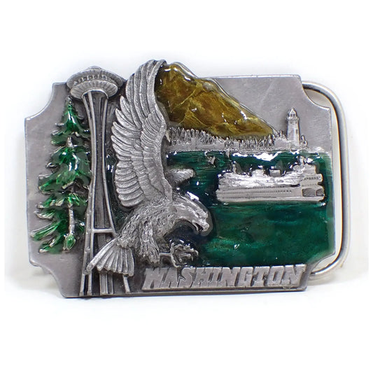 Front view of the retro vintage Siskiyou souvenir belt buckle. It is for the state of Washington and has a depiction of an eagle, a ferry on water, Mount St Helens, a lighthouse, and the Space Needle on the front. There is green enamel on the water and on the tree by the eagle. The mountain is a yellow and brown enamel.