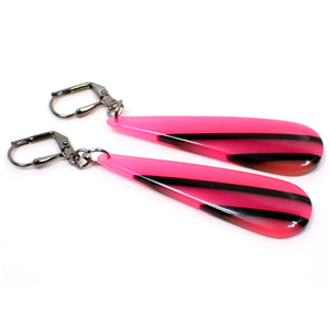 Angled enlarged view of the handmade drop earrings made with vintage resin beads. The metal is gunmetal gray in color. There are long thinner style teardrop beads that are slightly domed on the front. They are bright pink in color with black diagonal stripes.
