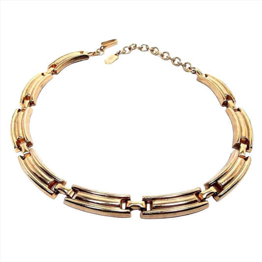 Front view of the Mid Century vintage Jaycraft link choker necklace. It is gold tone in color. There are curved rectangle links all the way to the hook clasp and chain end. There is a hang tag at the end of the chain.