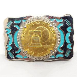 Front view of the retro vintage belt buckle. It is silver tone in color that has an abstract and heart cut out areas with blue enamel inside. The middle has a gold tone color replica dollar coin of the Liberty Bell and moon.