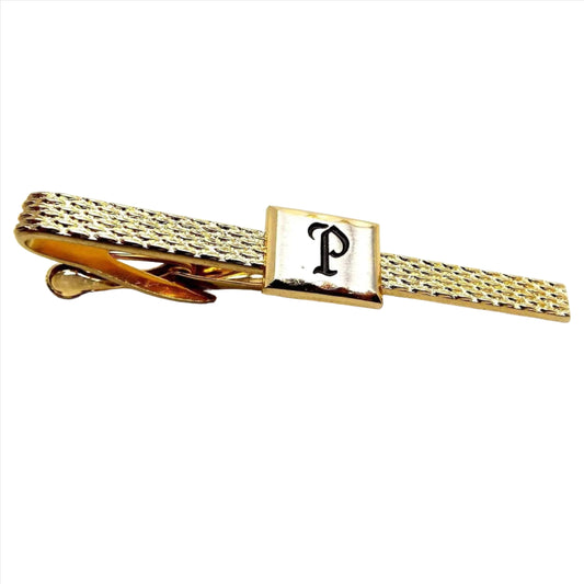 Angled front view of the Mid Century vintage Hickok initial tie clip. It is textured gold color with a rectangle in the middle. The rectangle has the letter P engraved on it and painted black.