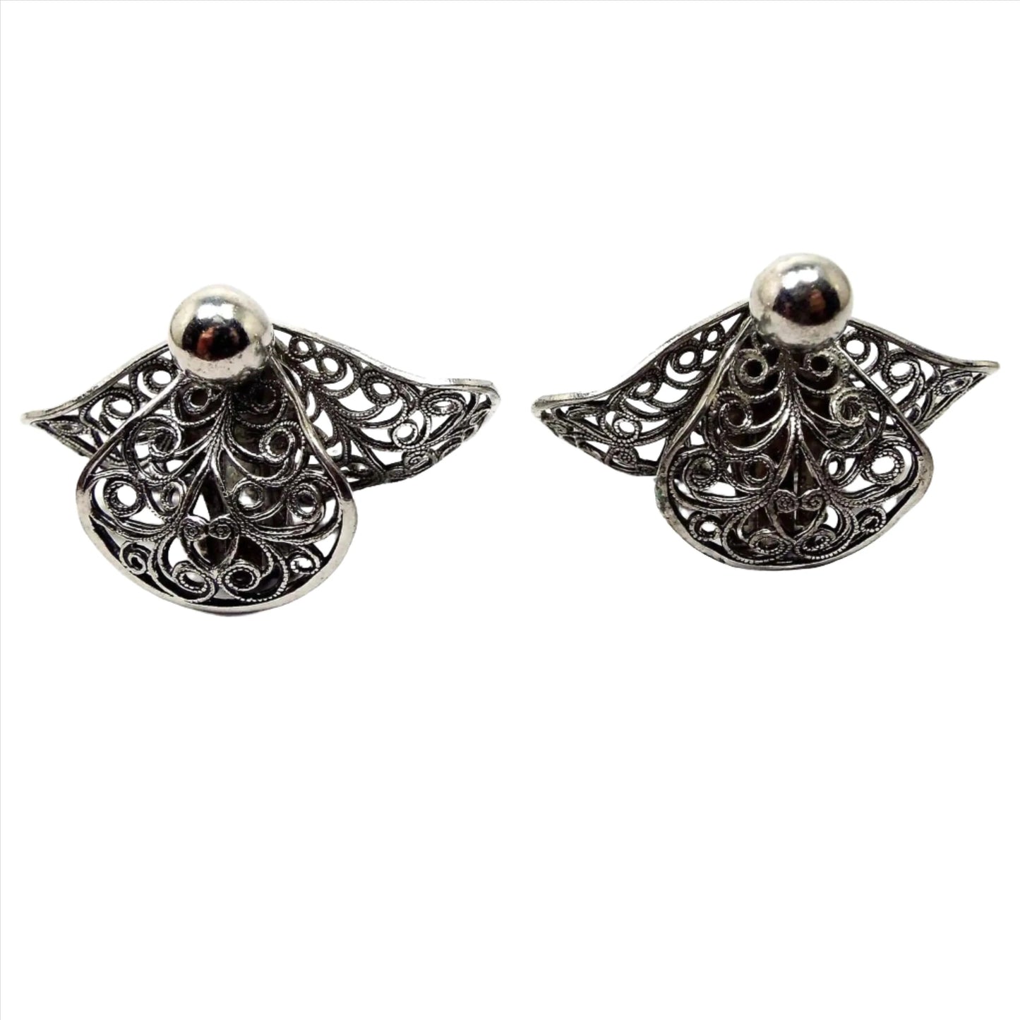Front view of the Mid Century vintage filigree clip on earrings. They are a darker silver tone in color with a curved filigree fan like shape.