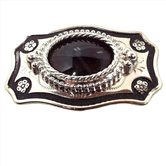 Front view of the retro vintage agate gemstone belt buckle. It is silver tone in color with black painted edge and flowers at the corners. There is an oval agate cab in the middle that is very dark brown almost black in color.