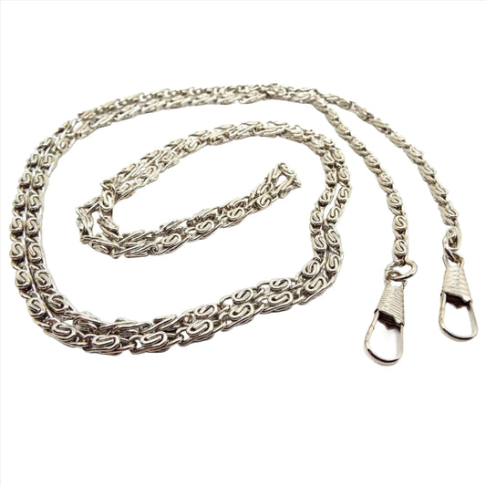 Angled view of the retro vintage long fob chain. The metal is silver tone in color. The links are a S link snail chain link.