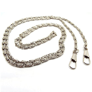 Angled view of the retro vintage long fob chain. The metal is silver tone in color. The links are a S link snail chain link.