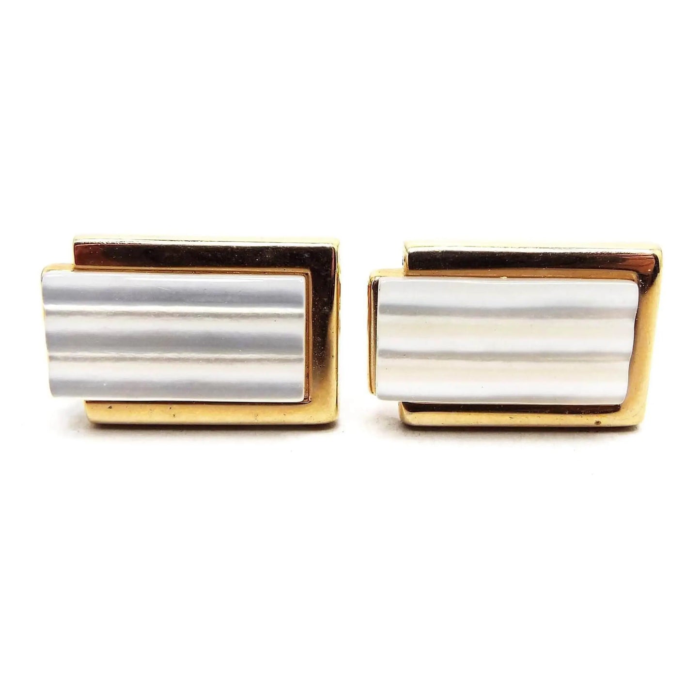 Front view of the Mid Century vintage modernist Swank cufflinks. they have a rectangle design with gold tone color metal. There is a longer rectangle in the middle that extends past one side with pearly white carved mother of pearl shell cabs.
